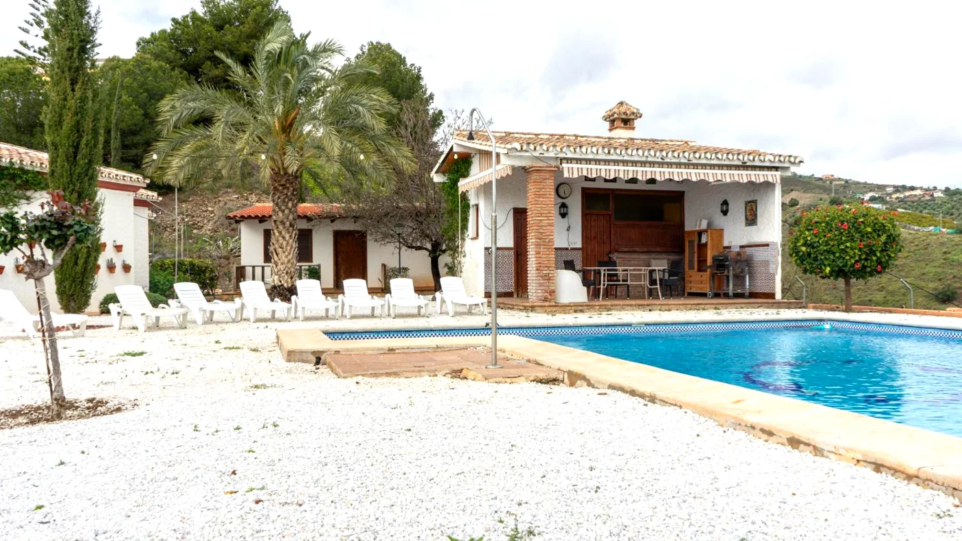 Piscina con tumbonas y la casa al fondo